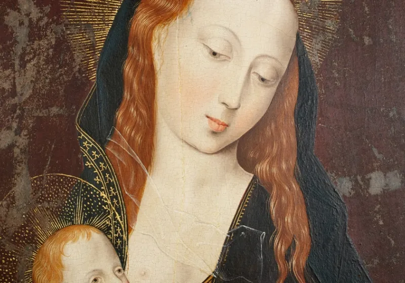 Primer pla d’una pintura religiosa antiga: la Mare de Déu, de pell clara i cabells rogencs, inclina suaument el cap amb expressió serena mentre sosté l’Infant Jesús. Tots dos tenen halos daurats; el fons és fosc i desgastat, amb signes d’envelliment de l’obra.