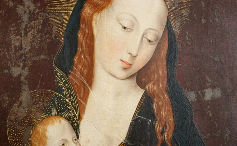 Primer pla d’una pintura religiosa antiga: la Mare de Déu, de pell clara i cabells rogencs, inclina suaument el cap amb expressió serena mentre sosté l’Infant Jesús. Tots dos tenen halos daurats; el fons és fosc i desgastat, amb signes d’envelliment de l’obra.