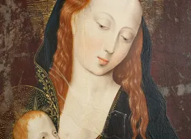 Primer pla d’una pintura religiosa antiga: la Mare de Déu, de pell clara i cabells rogencs, inclina suaument el cap amb expressió serena mentre sosté l’Infant Jesús. Tots dos tenen halos daurats; el fons és fosc i desgastat, amb signes d’envelliment de l’obra.